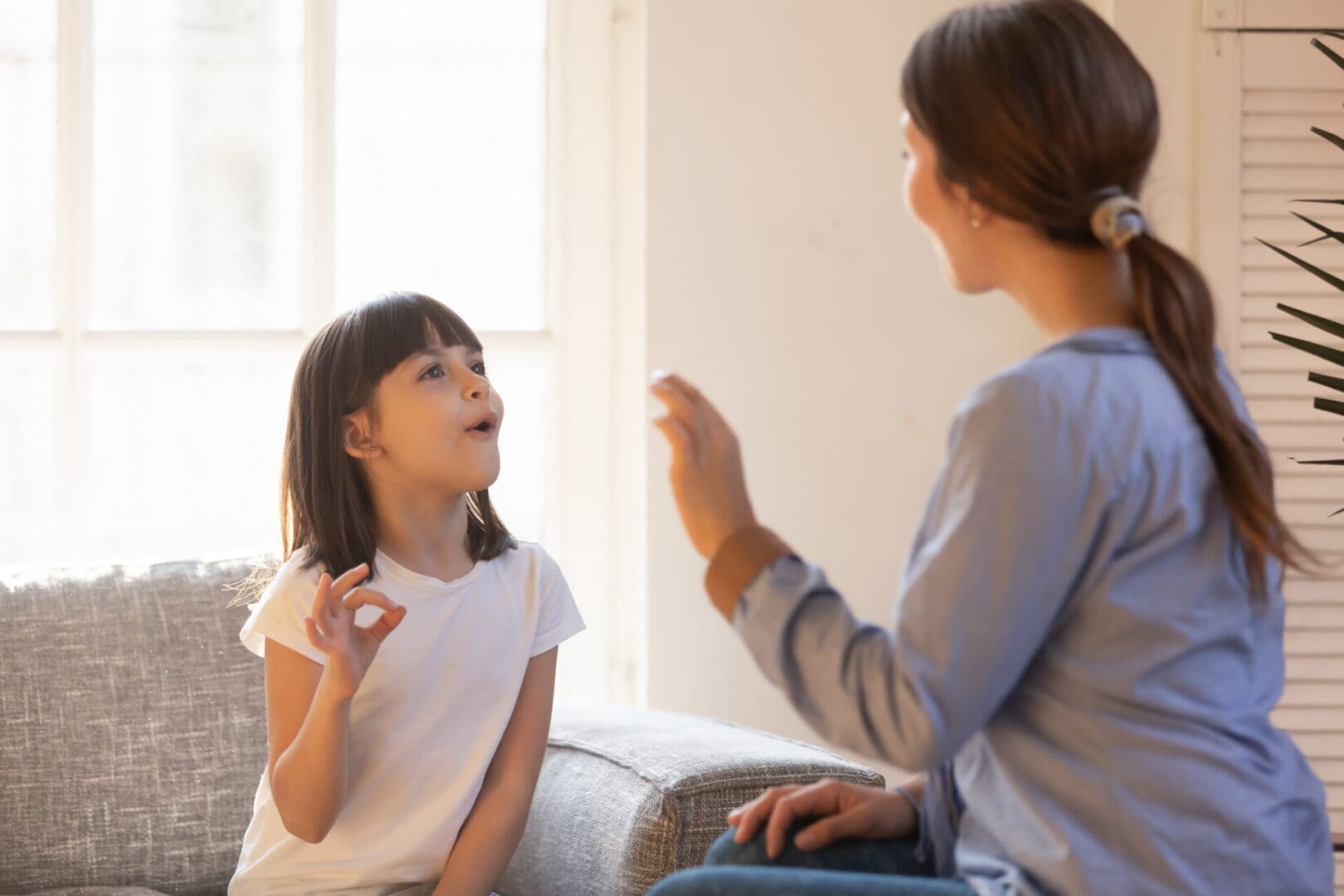 Woman teaching girl sign language.