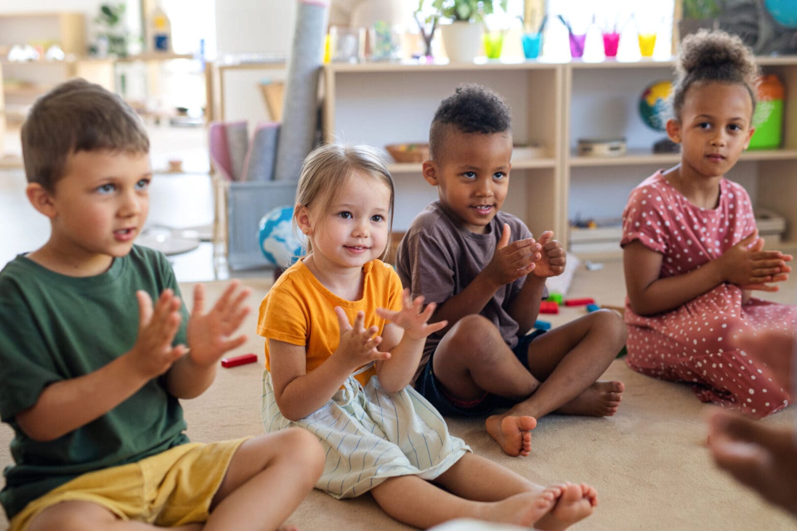 Four children clapping in classroom.